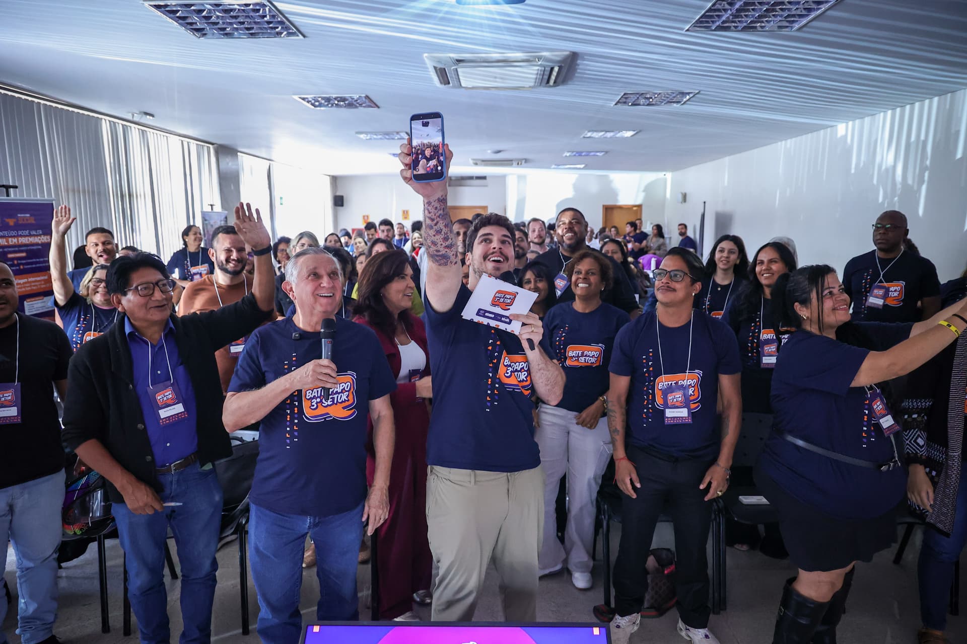 Participantes de um encontro do Bate Papo 3º Setor reunidos, sorrindo e com as mãos levantadas